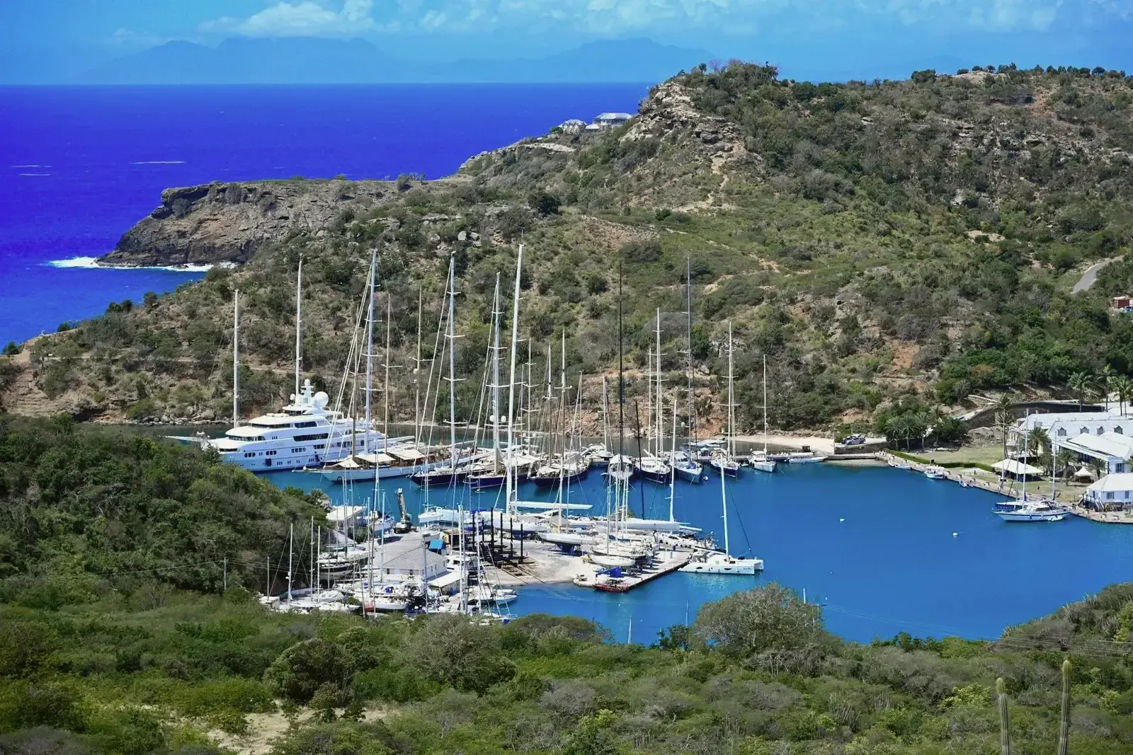 Marina resguardada entre colinas verdes en una bahía caribeña, con veleros y yates amarrados